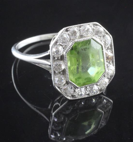 An early 20th century platinum, emerald cut peridot and diamond cluster ring, size O.